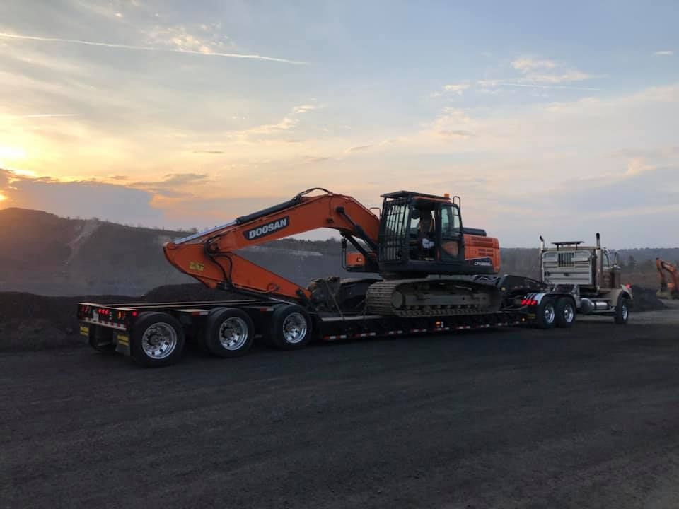 A large orange excavator is sitting on top of a trailer.