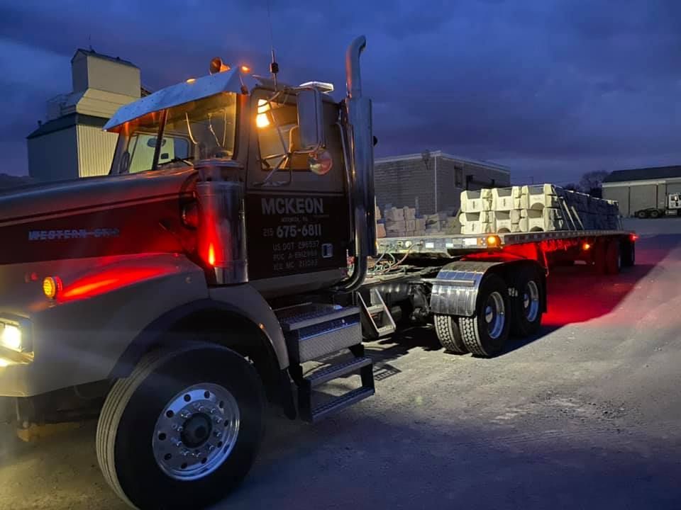 A large semi truck is parked in a parking lot at night.