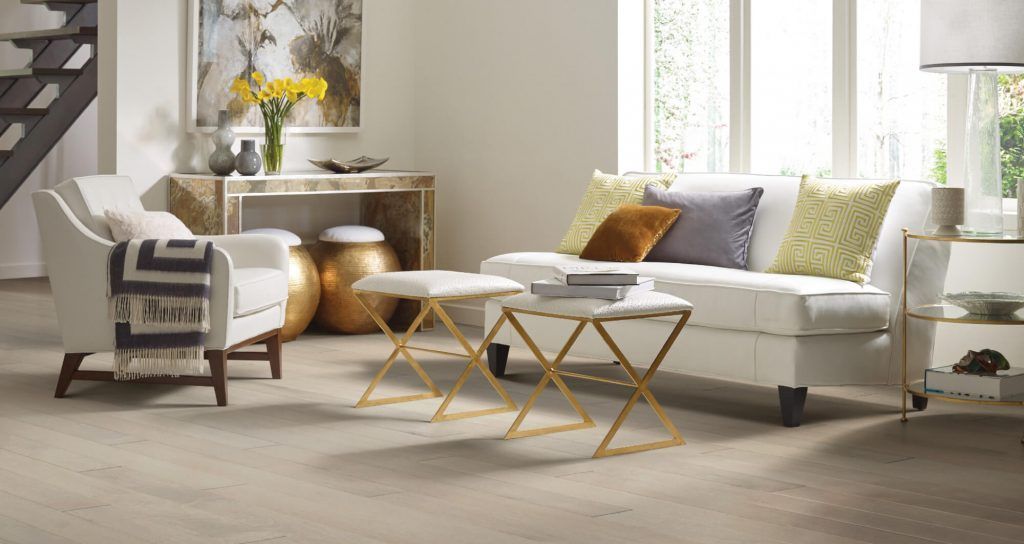 Living room with white sofa, armchair, gold accents, and bright window.