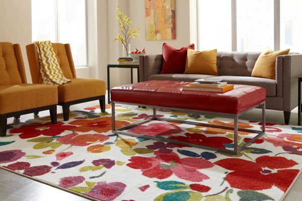 Living room with floral rug, gray sofa, orange chairs, red ottoman.