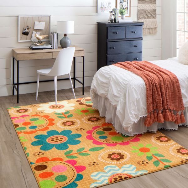 Bedroom with floral rug, desk, bed, and dresser. Orange, blue, green, and pink colors.