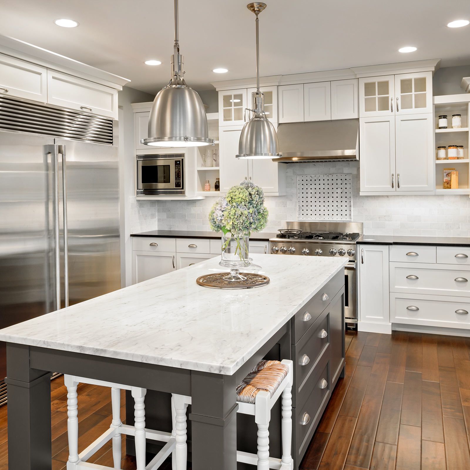 Kitchen with white cabinets, stainless steel appliances, and a gray island with a marble countertop.