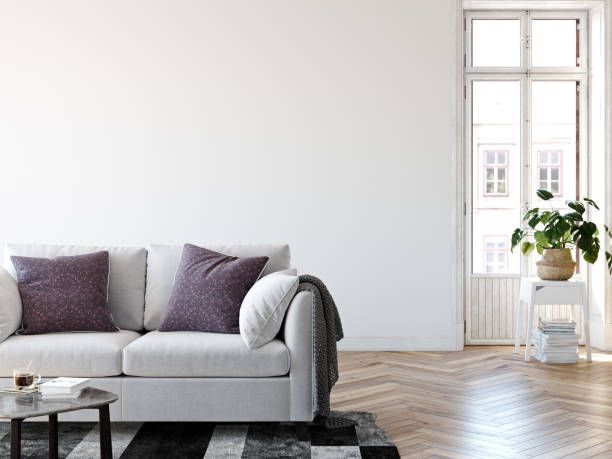 White living room with a couch, table, rug, window, and plant.