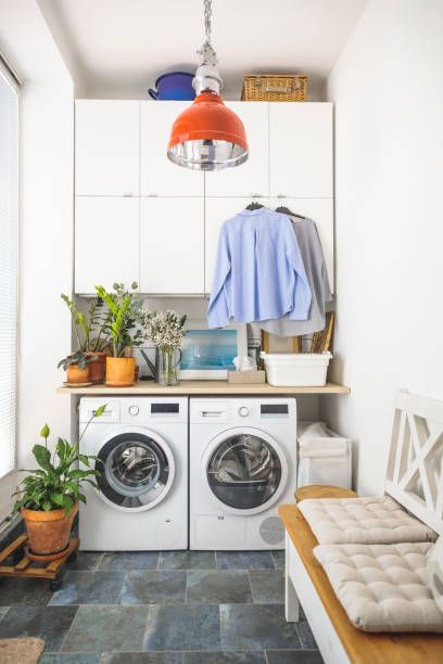 Laundry room with white appliances, overhead lighting, bench, plants, and blue tiled floor.