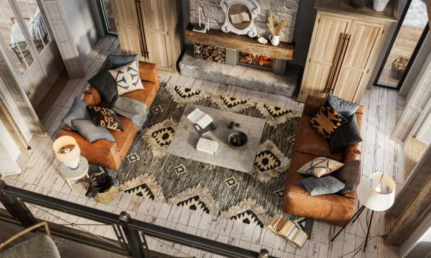 Cozy living room with leather sofas, patterned rug, fireplace, and wooden furniture. High-angle view.