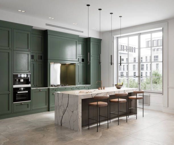 Green kitchen with marble island, stools, and large window.