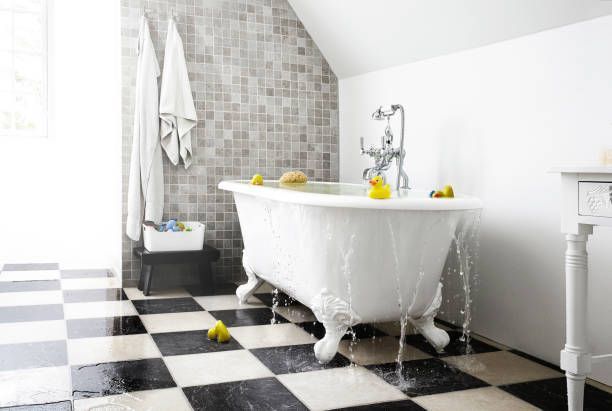 Bathtub overflowing, water on black and white checkered floor, rubber duckies present.