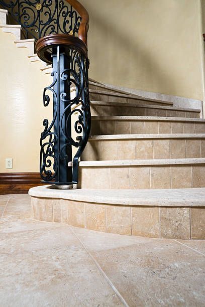 Stone curved staircase with wrought iron railing.