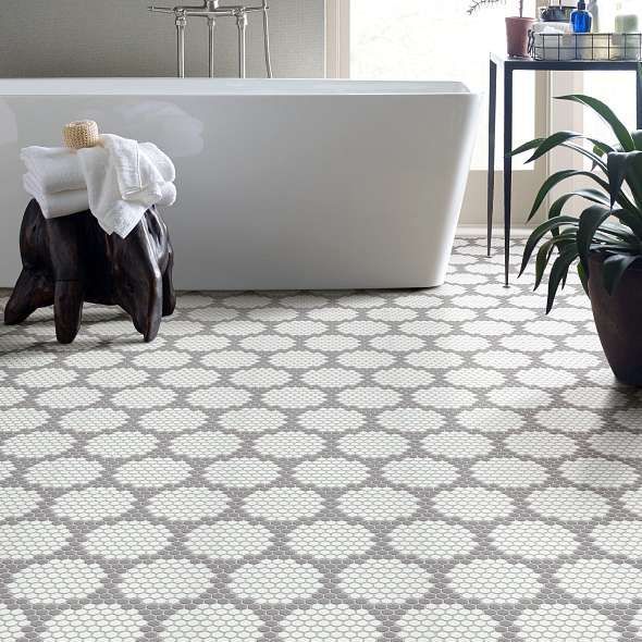 Bathroom with white soaking tub, decorative hexagon tile floor, and potted plant.