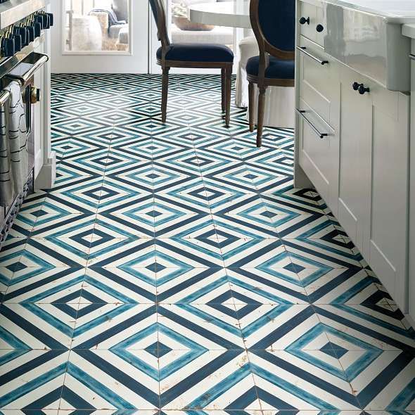 Kitchen floor with geometric blue and white diamond tile pattern. White cabinets and a stove are visible.