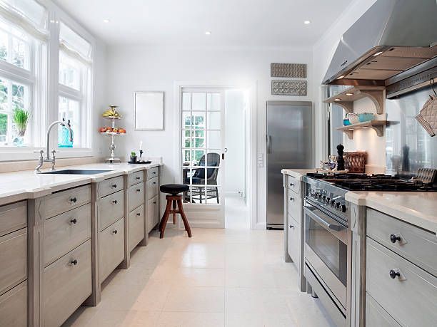 Bright, white kitchen with gray cabinets, stainless steel appliances, and a window overlooking a bright space.