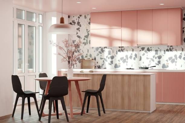 Pink kitchen with a round table and black chairs, natural wood accents, and terrazzo backsplash.
