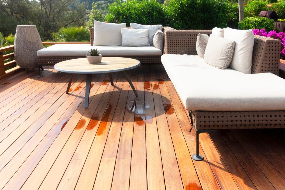 Outdoor patio with wooden deck, wicker furniture, and round table.