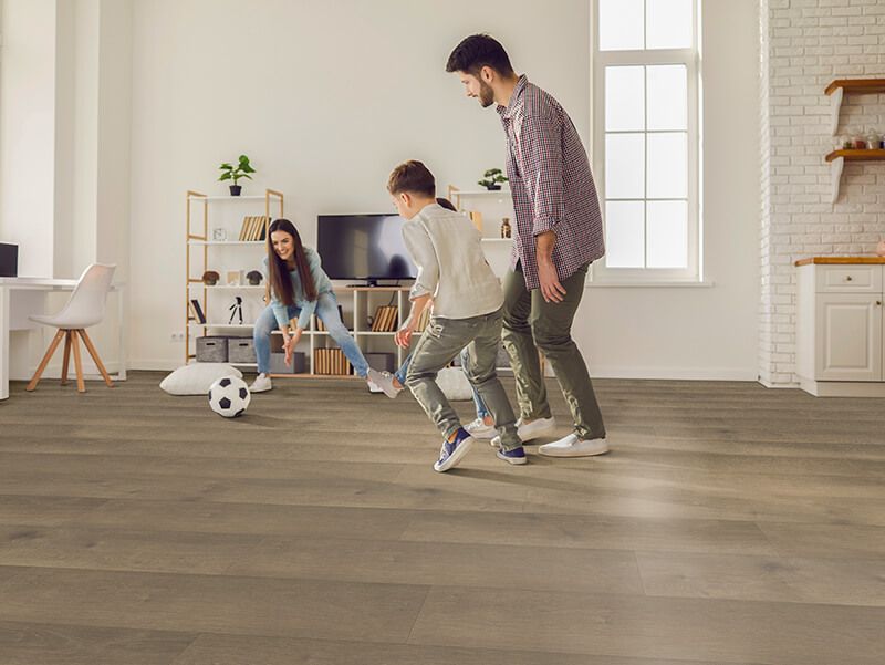 Family playing soccer in a living room with wooden floors.