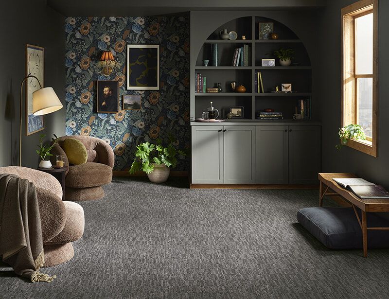 Cozy room with floral wallpaper, built-in shelving, two armchairs, and a low table by a window.