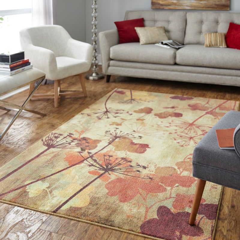 Living room with floral rug, beige sofa, white chair, and wooden floor.