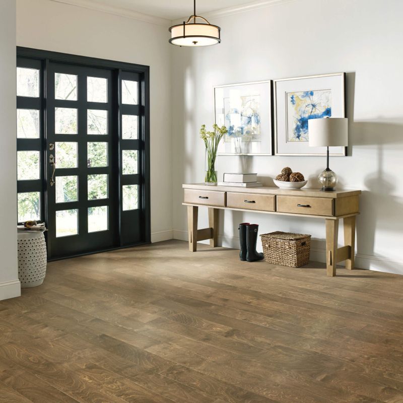 Entryway with wood floors, black door, and a wooden console table with decor.