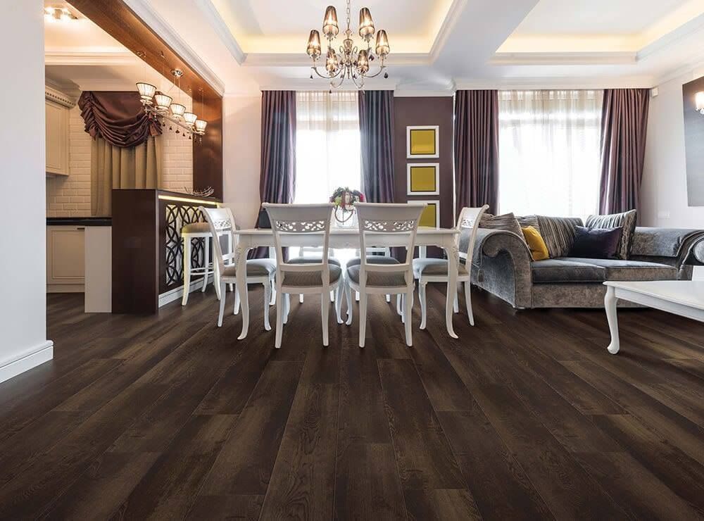 Dining room with dark wood floors, white dining set, and gray couch.