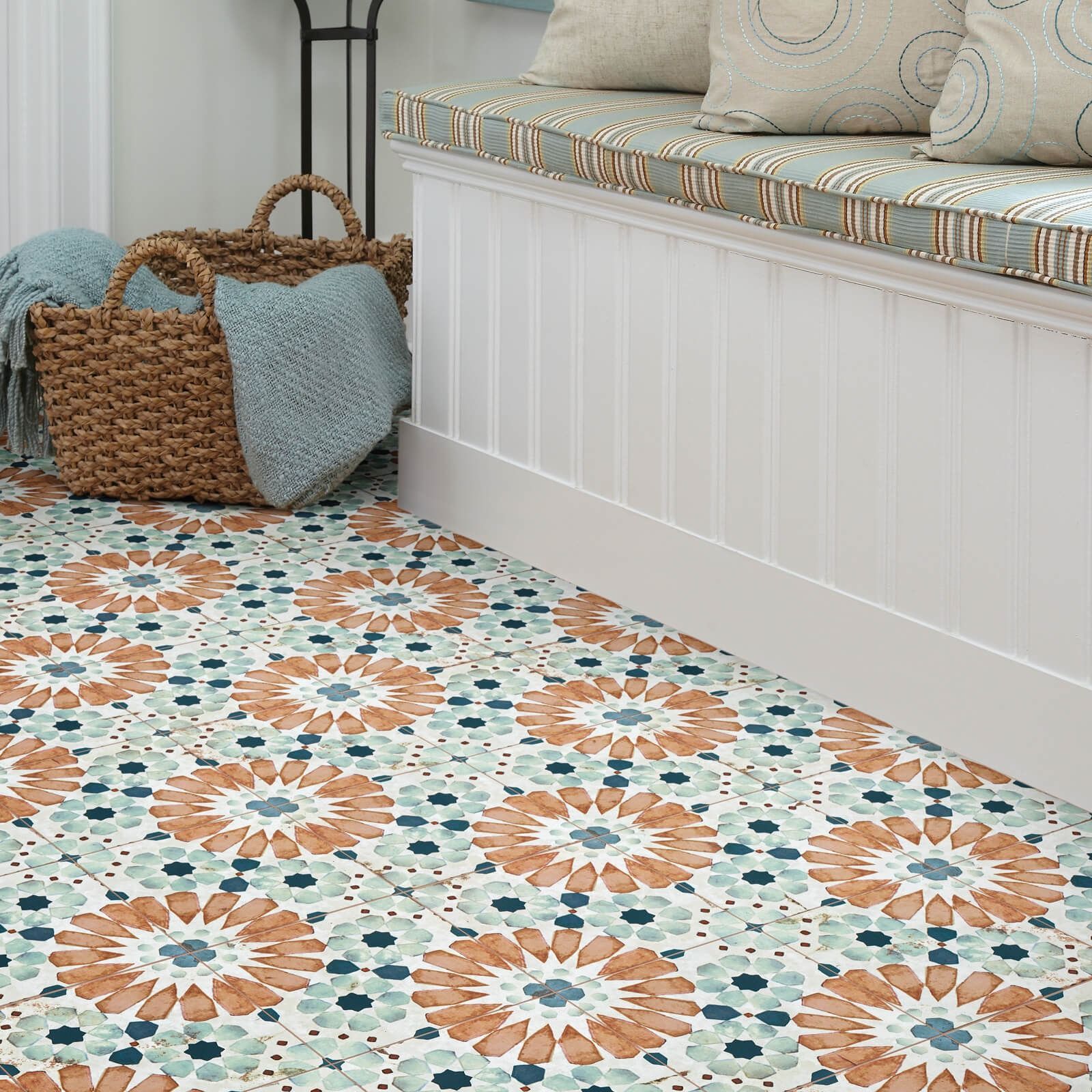 Floral tile floor with bench, pillows, and woven basket with blue throws.