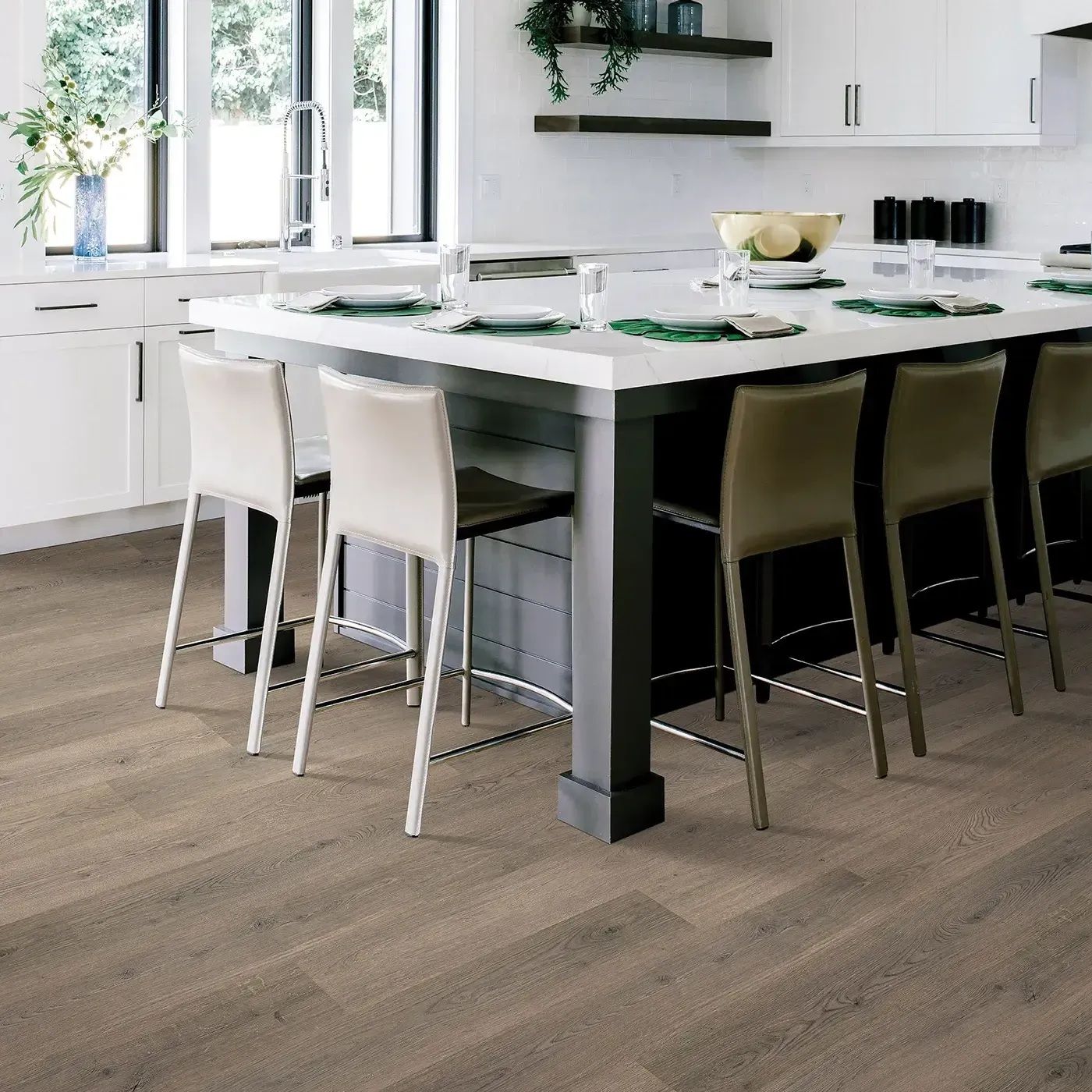 Kitchen with a white island, bar stools, and grey wood-look flooring. White cabinets and a window are visible.