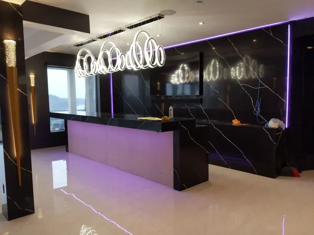 Modern black-and-white kitchen with purple accents, glossy floor, island, and hanging circular chandelier