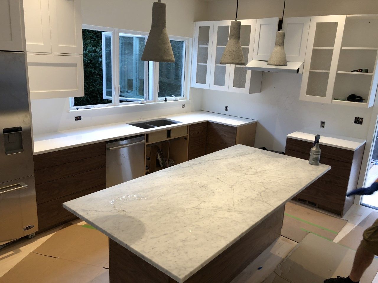 Modern kitchen with white cabinets, marble island, and large window over the sink