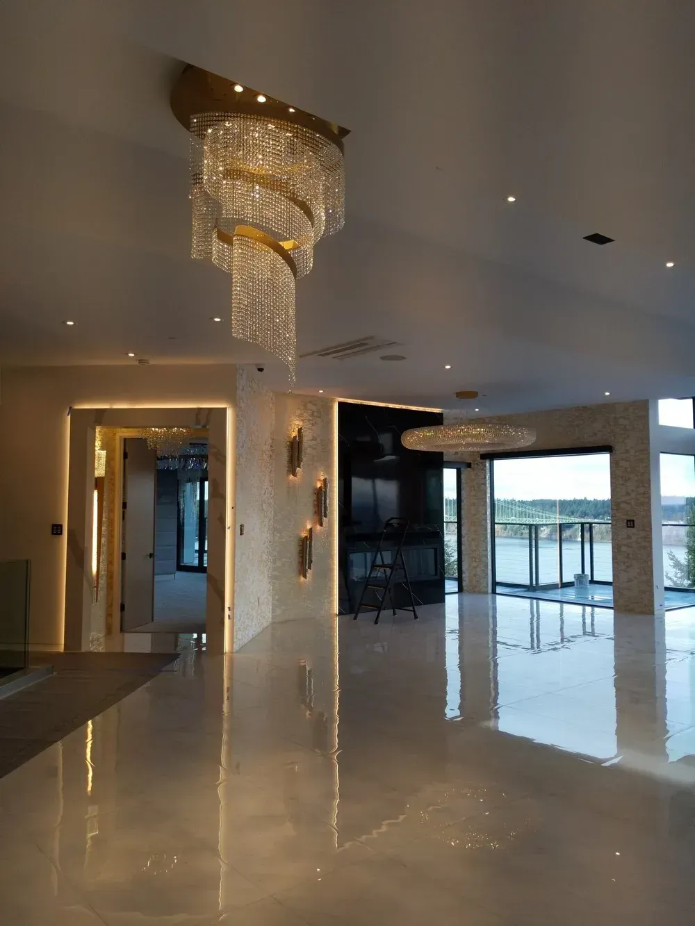 Modern luxury living room with glossy floors, crystal chandeliers, and large windows overlooking a balcony