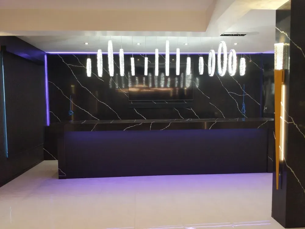 Modern hotel lobby with black marble walls, purple accent lighting, and a white reception desk