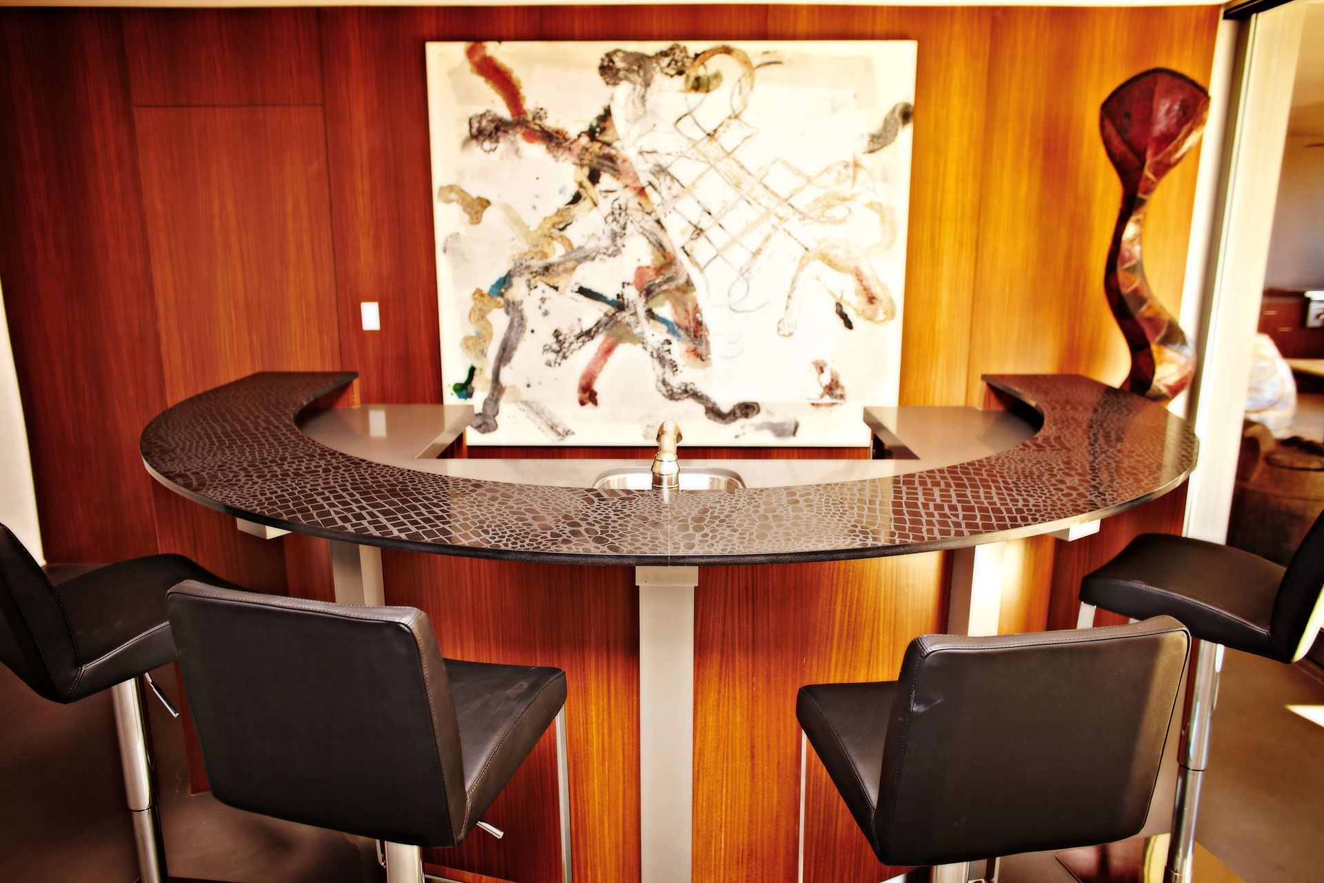 Modern lounge with a round wooden table, four dark chairs, and abstract art on the wall.
