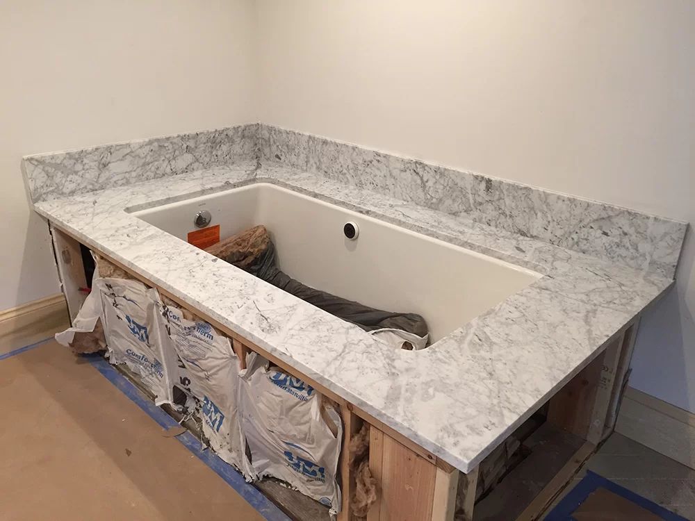 Half-installed marble-look vanity countertop around a rectangular sink base in a room under renovation