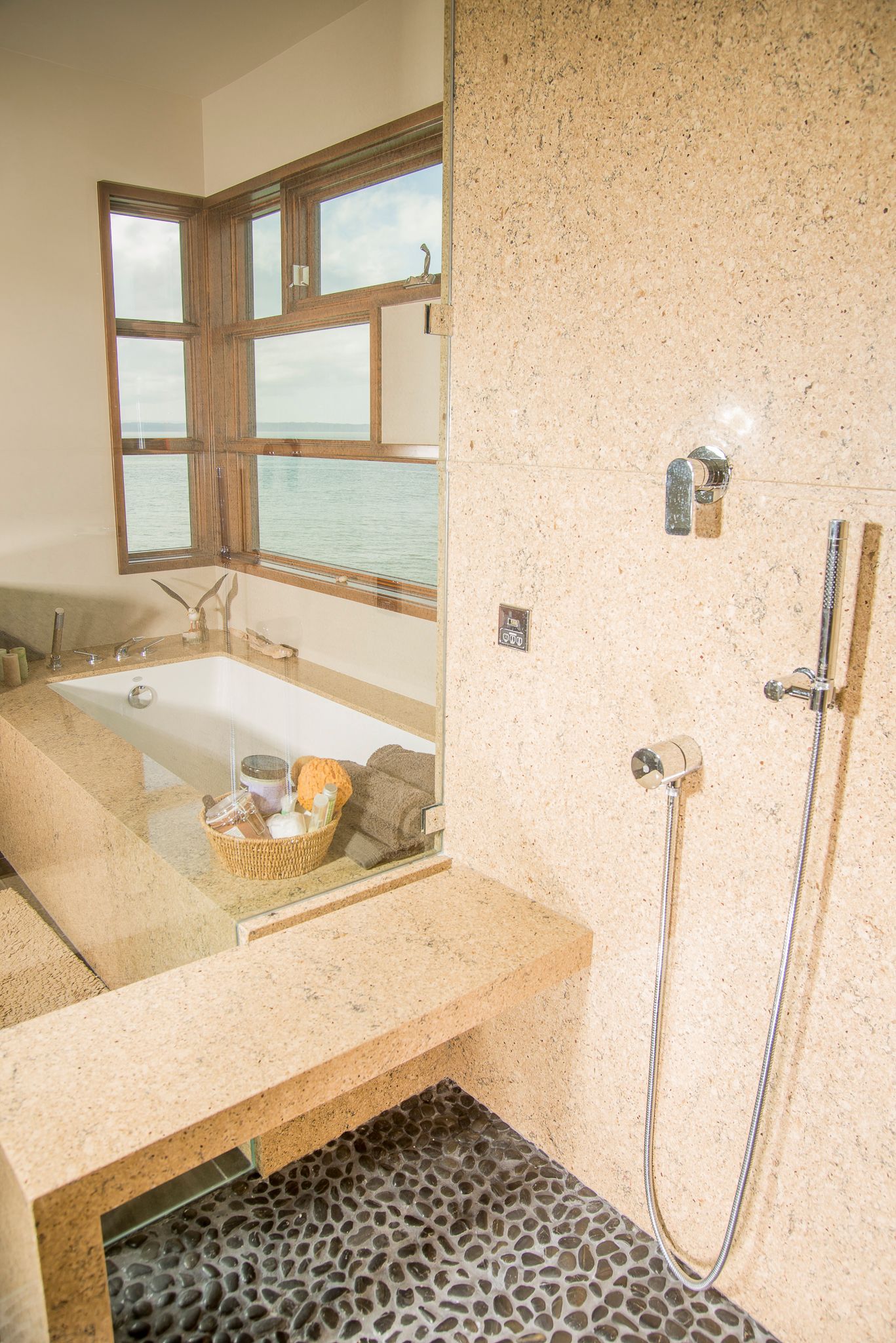 Small bathroom with a tub, window, speckled walls, and pebble-pattern shower floor.