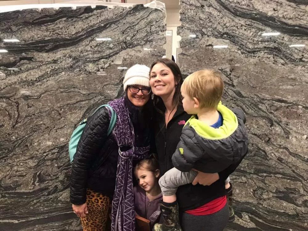 Three people posing for a photo on rocky terrain, with a child being held in front.