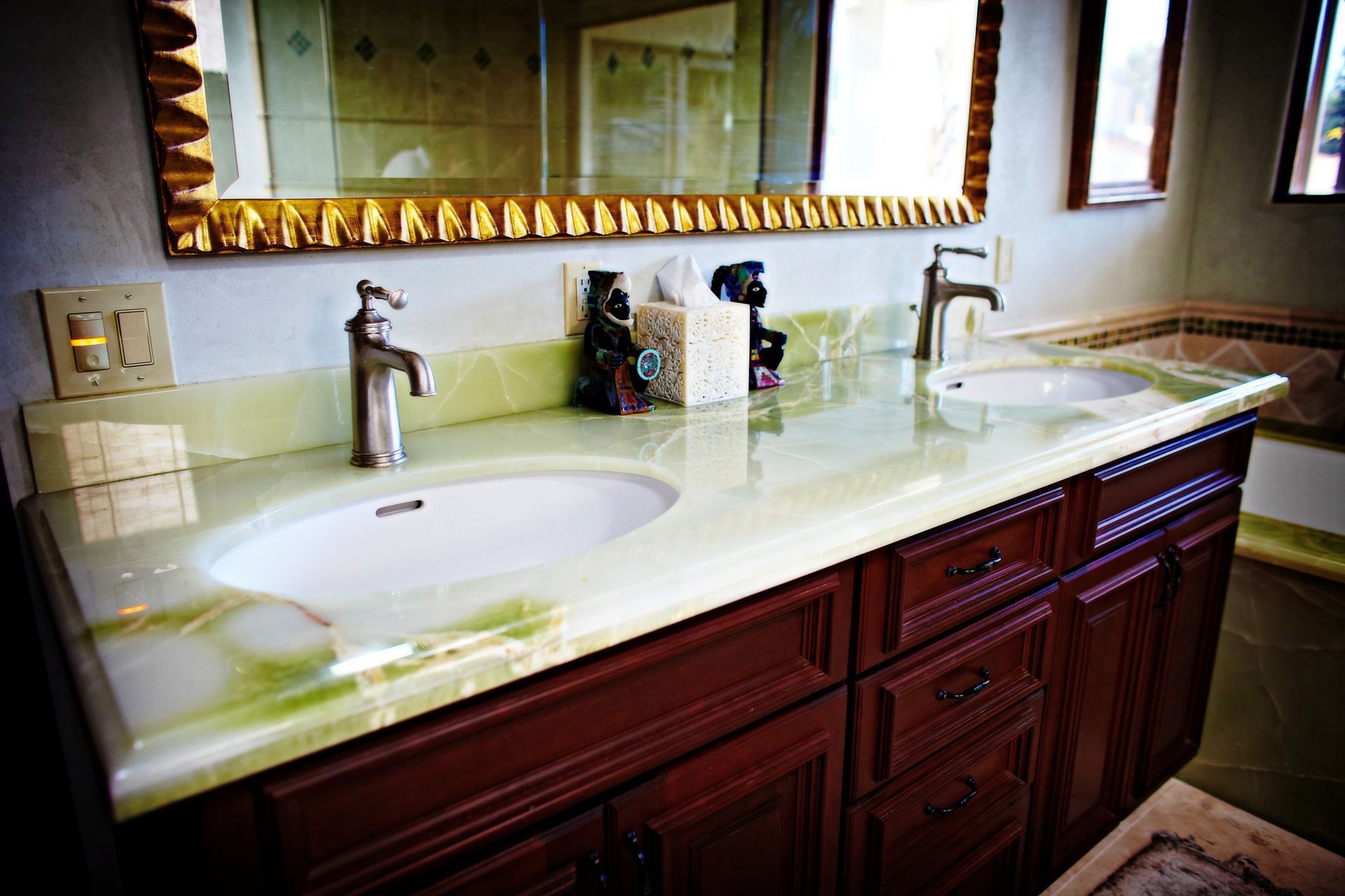 Bathroom vanity with double sinks, marble countertop, dark wood cabinets, and large mirror