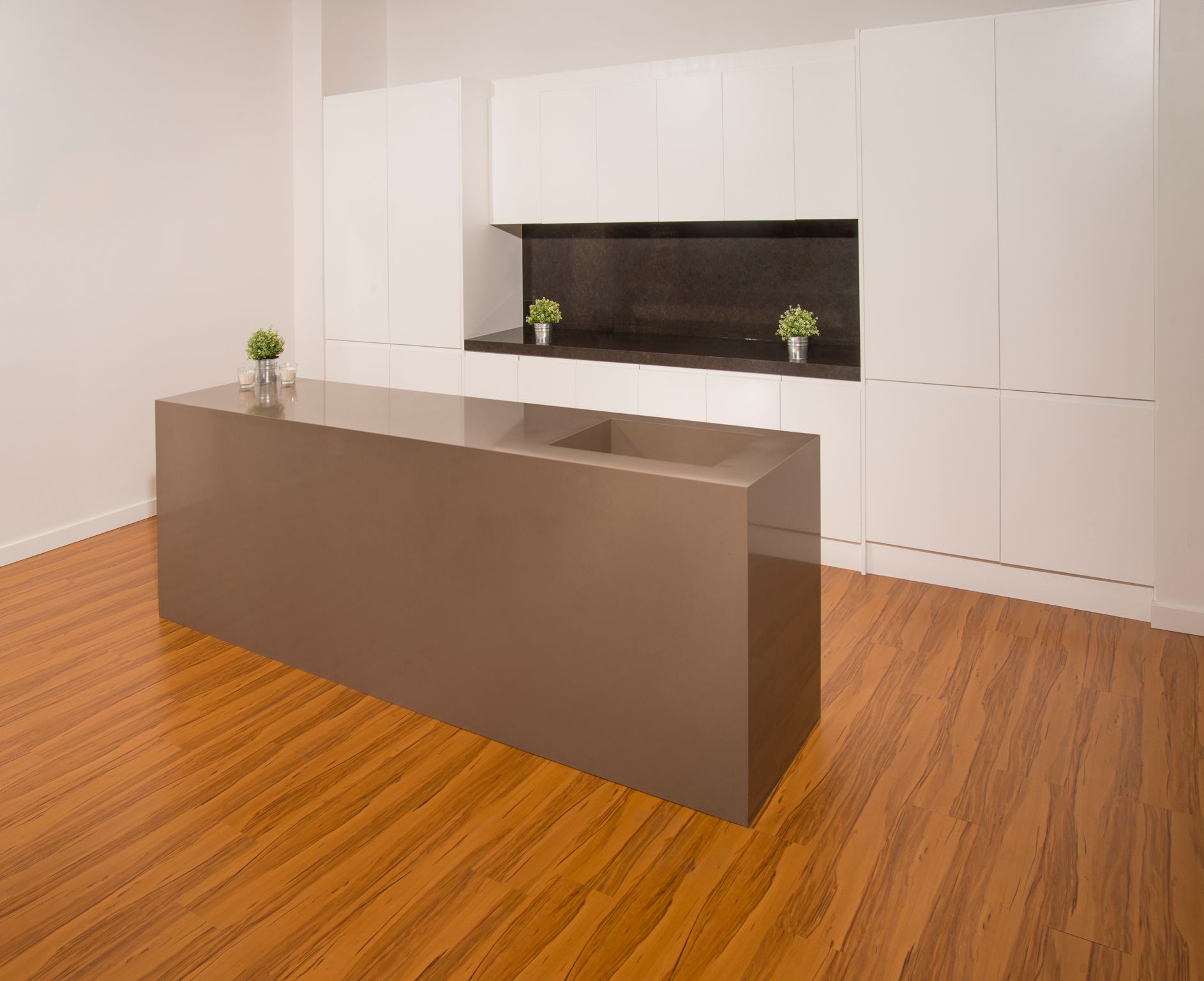 Modern minimalist office with a large brown desk and white wall cabinets