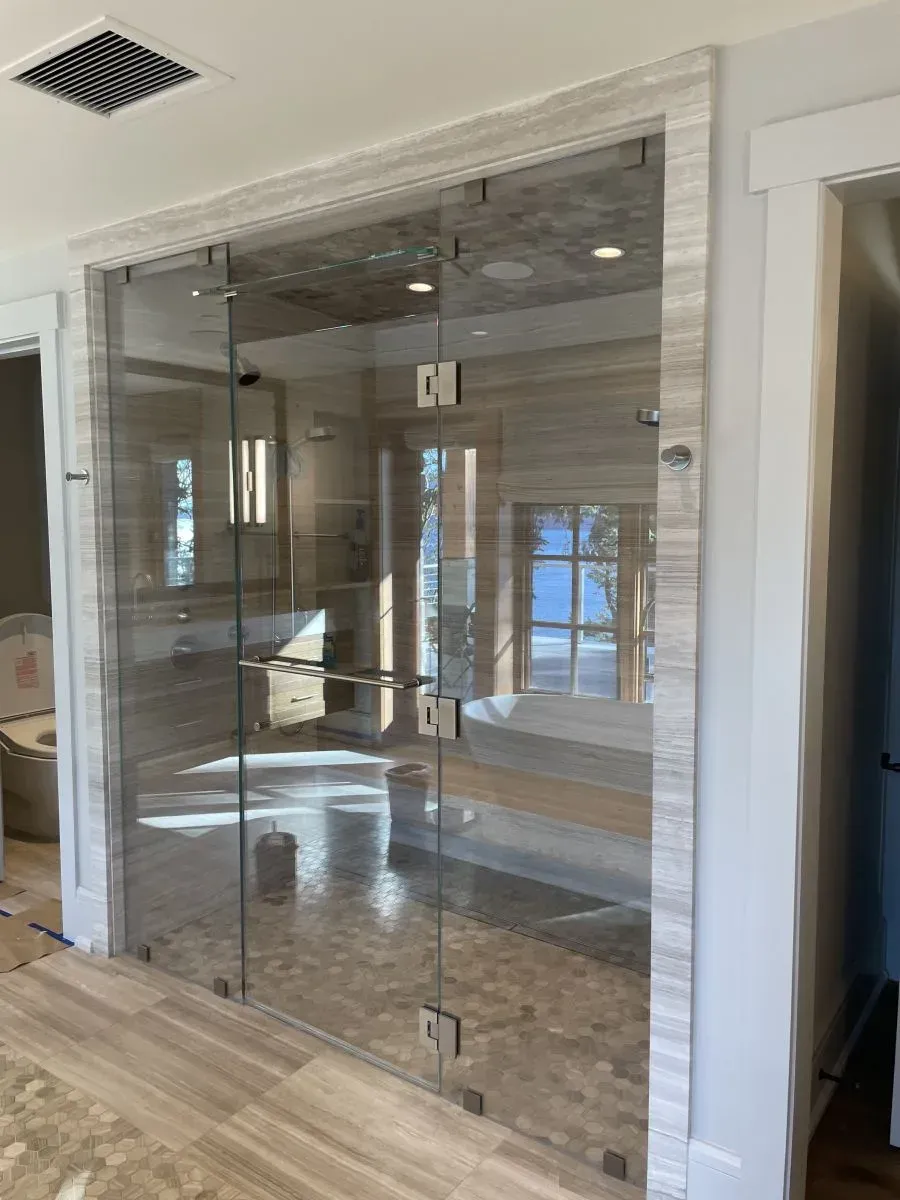 Glass-enclosed room with reflections, wood flooring, and recessed ceiling lights in a modern interior