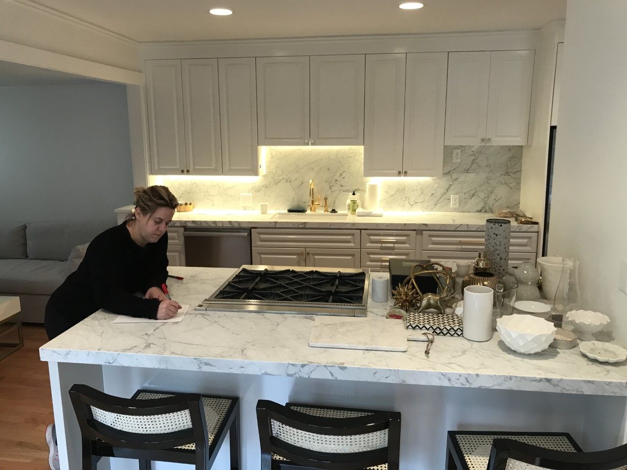 Person working at a marble kitchen island in a bright white modern kitchen