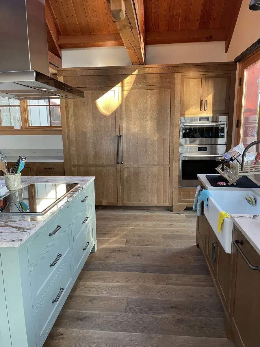 Modern kitchen with wood beams, large island, built-in oven, and light wood cabinetry