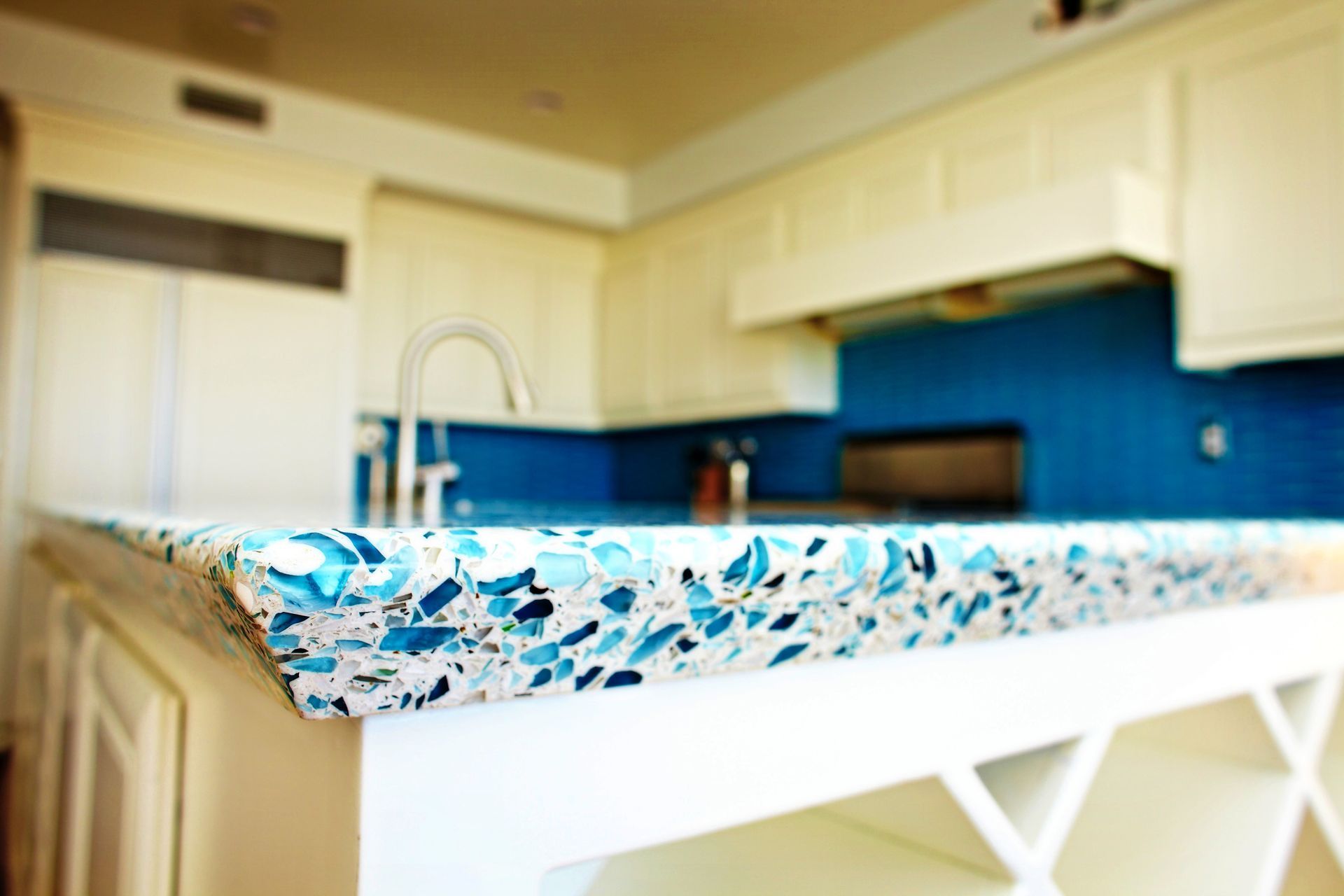 Bright kitchen with white cabinets, blue backsplash, and a colorful patterned countertop