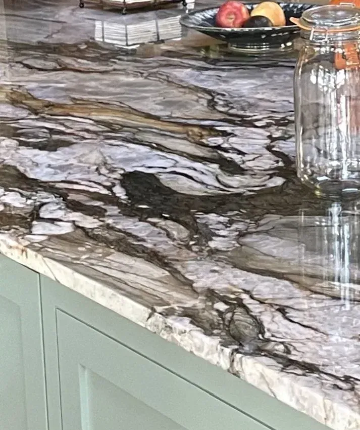 Marble-patterned kitchen countertop with a fruit bowl and a glass jar on top, above pale green cabinets