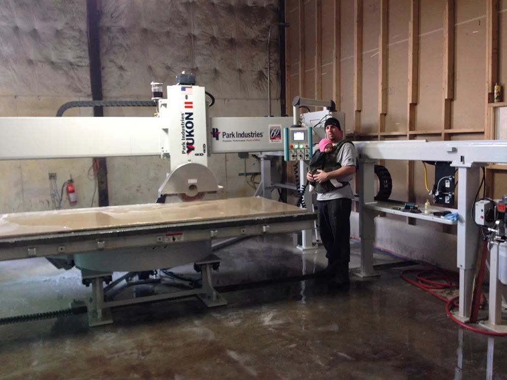 Worker operating a large industrial flatbed CNC machine in a workshop