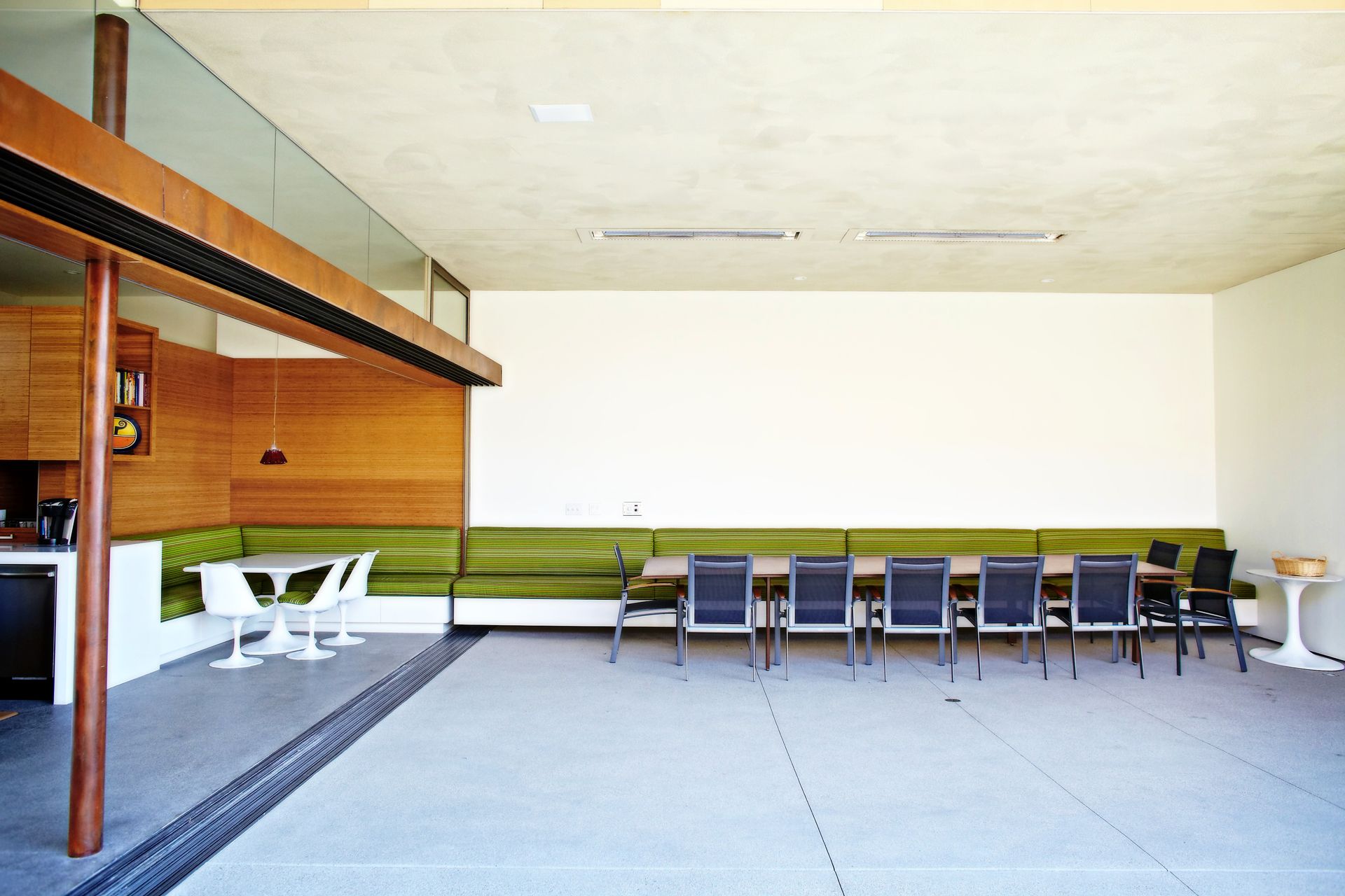 Empty modern room with long green bench seating and tables along the wall