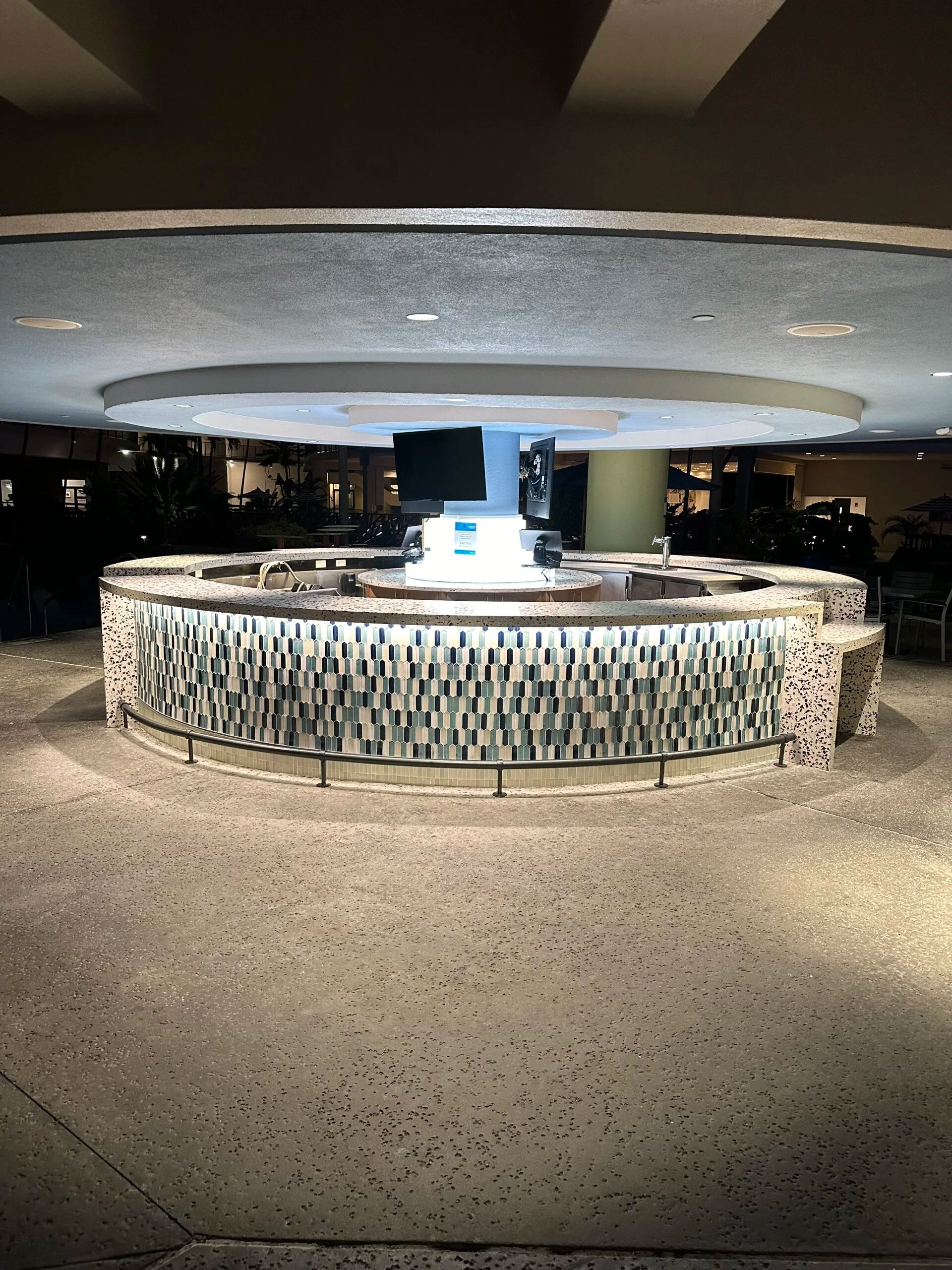 Round bar with mosaic-front counter in a dimly lit indoor lounge or lobby