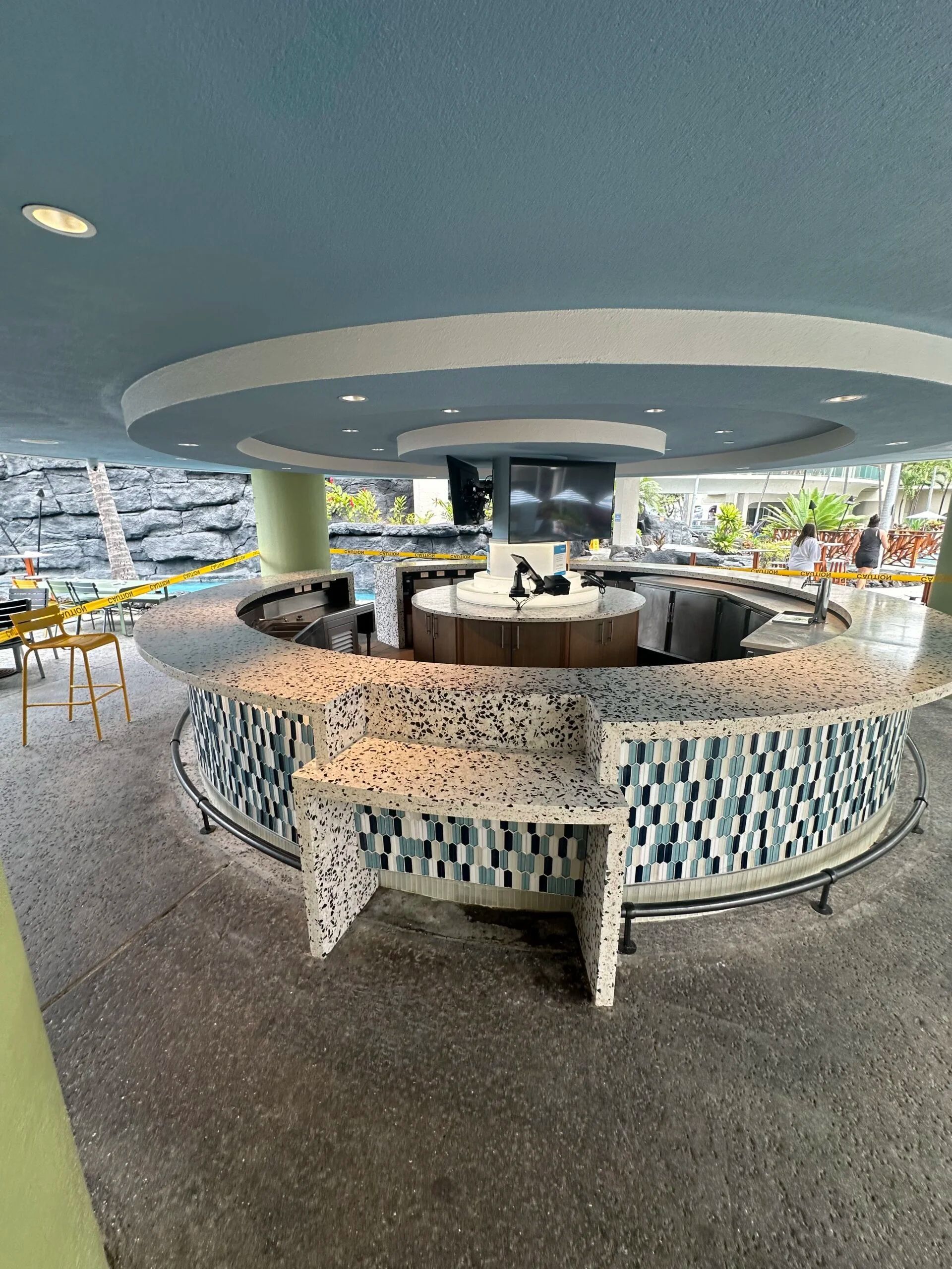 Circular indoor lounge with mosaic bar, tables, and ocean view through large windows