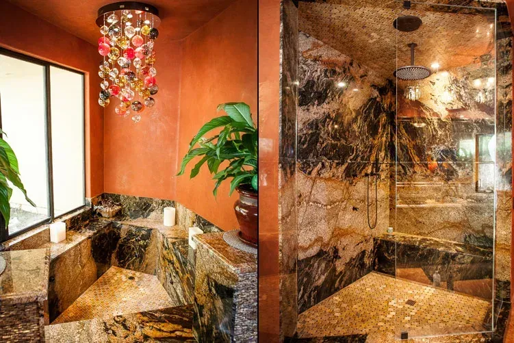 Orange bathroom with marble surfaces, potted plant, and glass-enclosed shower with mosaic tiles