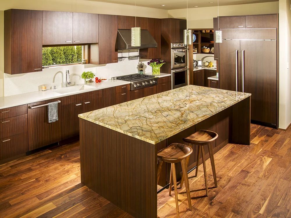 Modern kitchen with dark wood cabinets, granite island, stainless fridge, and hardwood floor