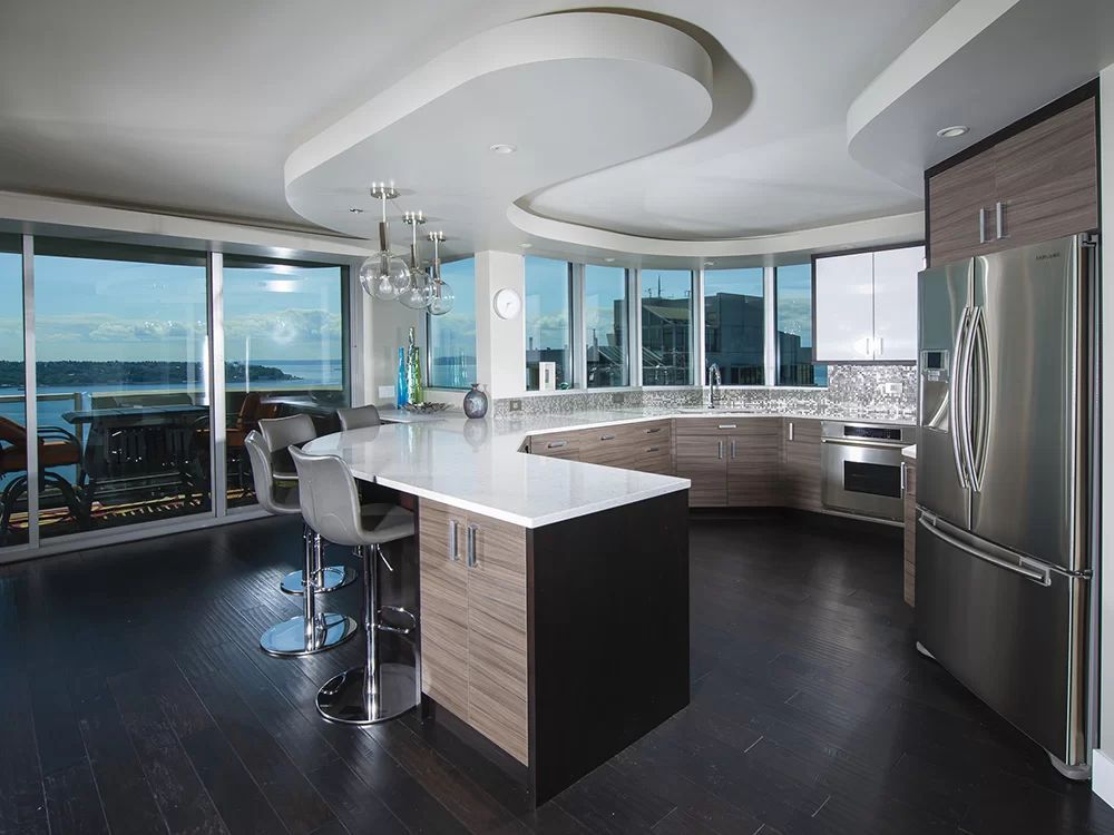 Modern kitchen with curved island, stainless appliances, and ocean-view windows