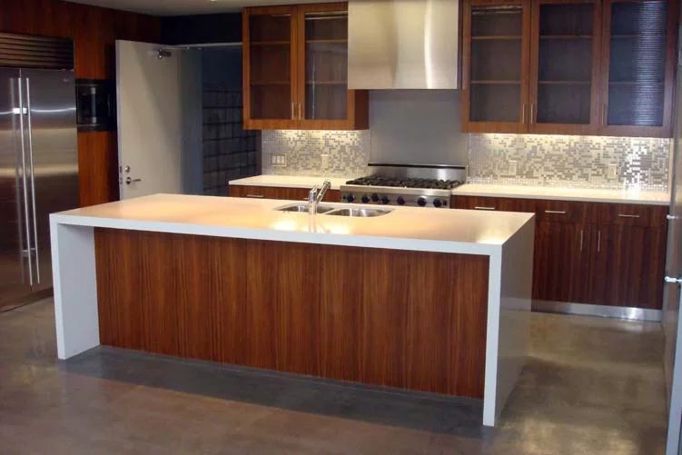 Modern kitchen with wood cabinetry, stainless steel appliances, and a large central island with white countertop
