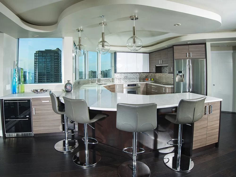 Modern kitchen with white island, gray bar stools, and city view through large windows