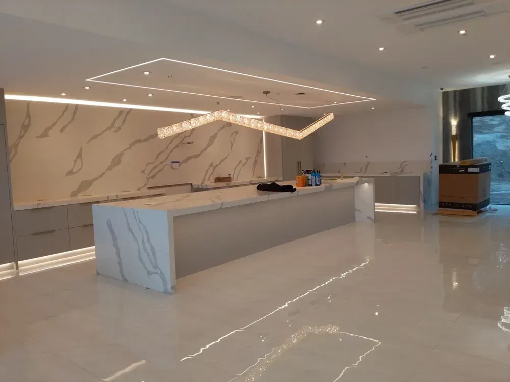 Modern hotel lobby with marble reception desk, glossy white floor, and warm ceiling lights
