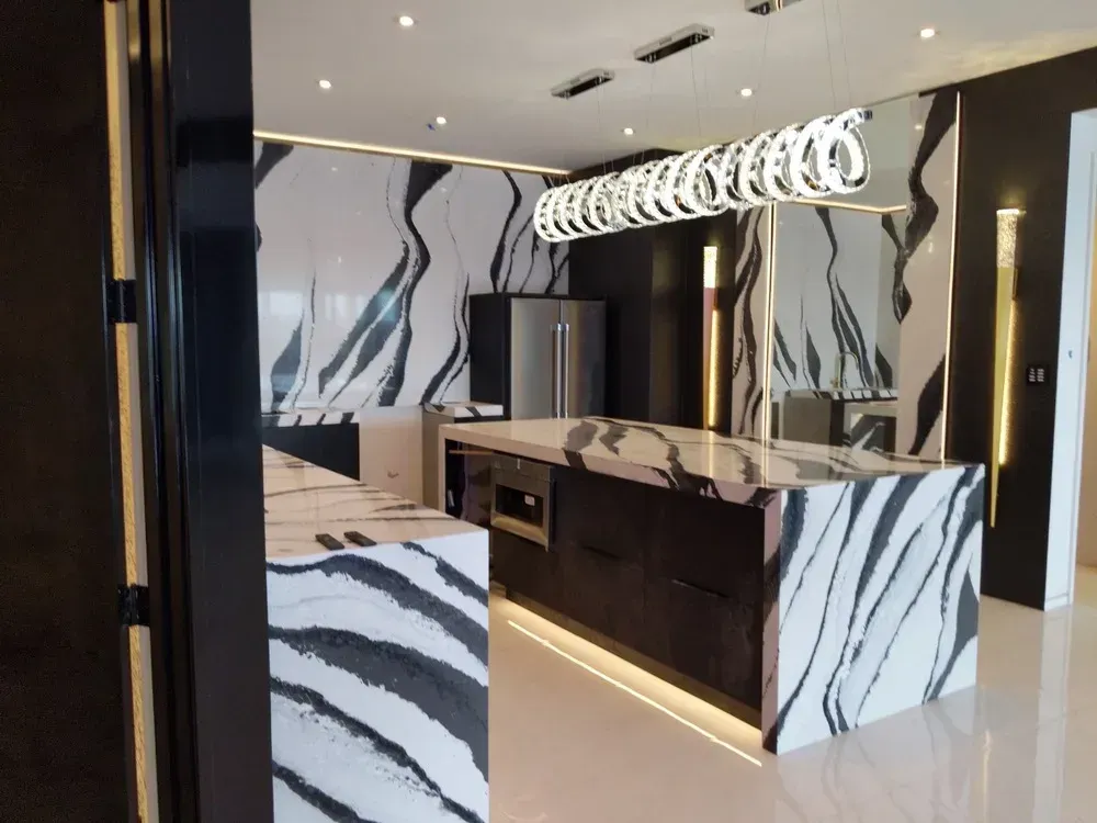 Modern kitchen with black, white, and marble-patterned cabinets, island, and pendant lights